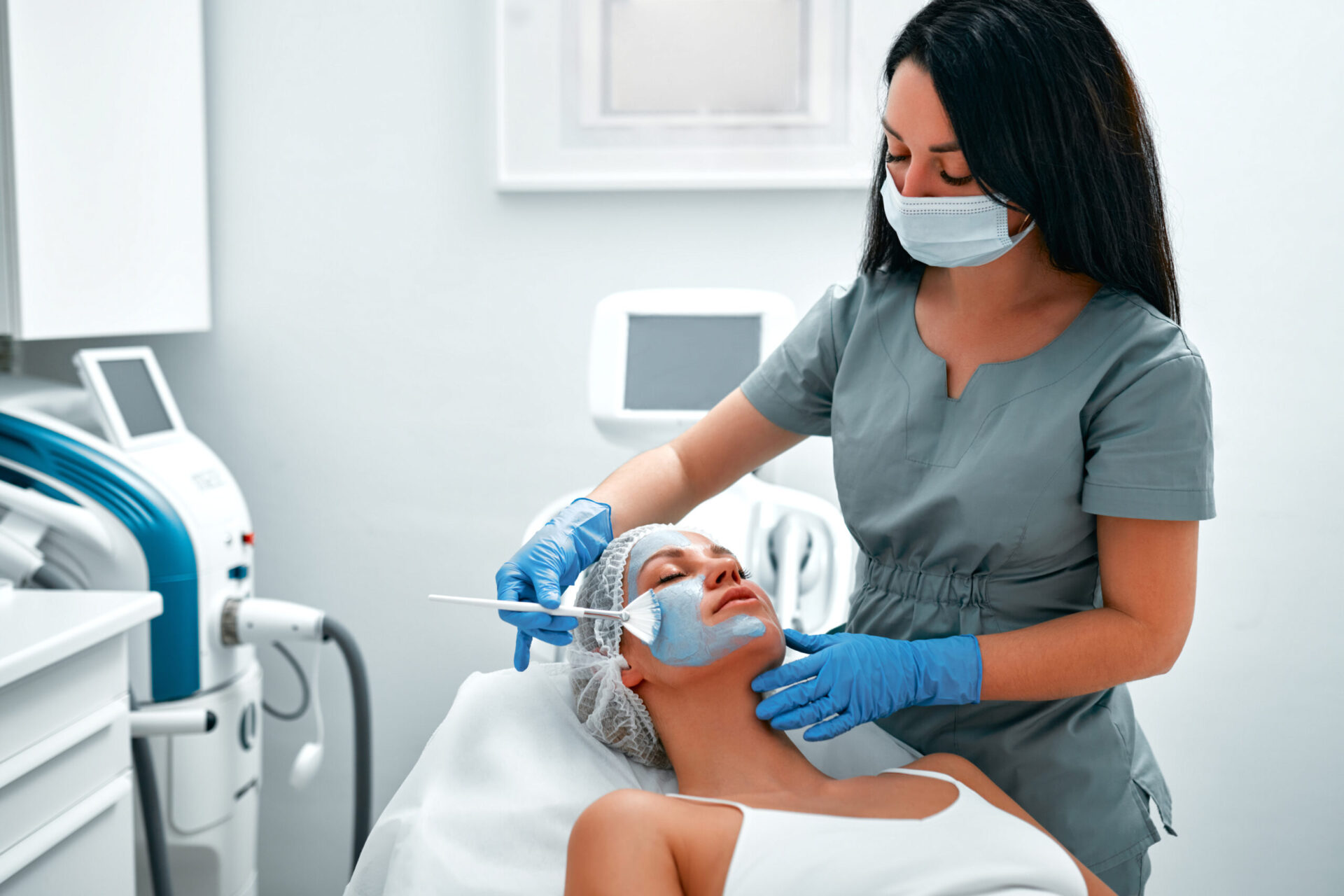Woman getting facial care by beautician at spa salon.